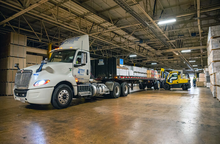 flatbed truck inside warehouse getting loaded by a forklift